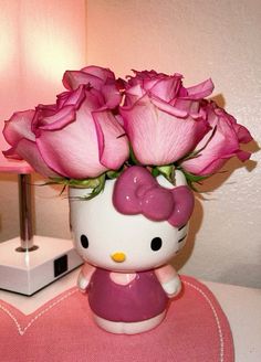 a hello kitty vase with pink roses in it