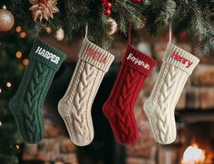 three christmas stockings hanging from a tree with the word happy written on them in red, white and green