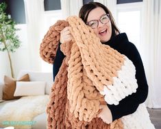 a woman holding up a giant chunky blanket in front of her face and smiling at the camera