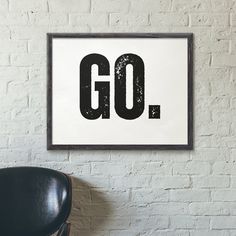 a black chair sitting in front of a white wall with the word go on it