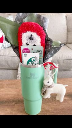 a coffee cup filled with christmas items on top of a table next to a stuffed animal