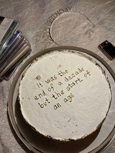 a white cake with writing on it sitting on a table next to cd's