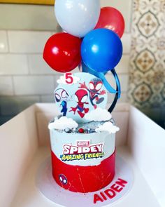 a spiderman birthday cake with balloons on top in a red cupcake box that says happy birthday