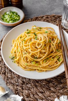 a white plate topped with pasta and chopsticks