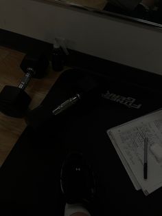 a person writing on a piece of paper next to a pair of black dumbbells