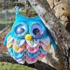 a crocheted owl sitting on top of a tree branch