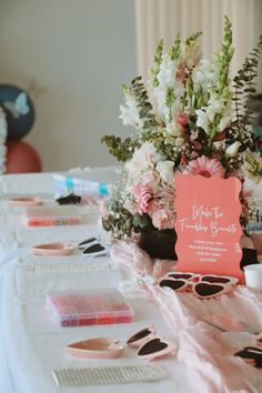 a table topped with lots of pink and white flowers on top of a white table cloth