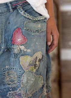 a person wearing ripped jeans with patches and hearts on them