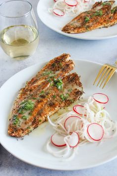 two white plates topped with fish and veggies