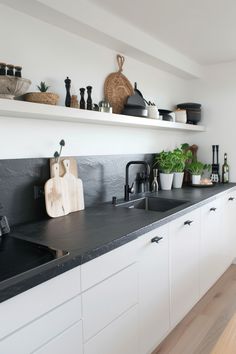 a kitchen with white cabinets and black counter tops, pots and pans on the shelves