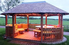 a wooden gazebo sitting on top of a lush green field