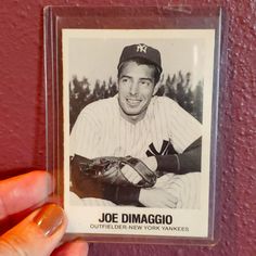 a person holding a baseball card in their left hand with the image of joe dimaggio on it