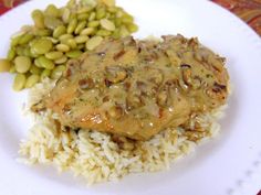 a white plate topped with rice and meat covered in gravy next to beans