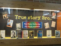 a display case filled with lots of books on top of a wooden shelf next to a brick wall