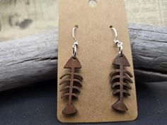 wooden earrings with fishbones on them sitting on top of a piece of wood