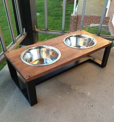 two stainless steel bowls sit on top of a wooden coffee table in front of a window