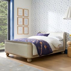 a bedroom with blue and white wallpaper has a bed in the middle, along with a wicker basket on the floor