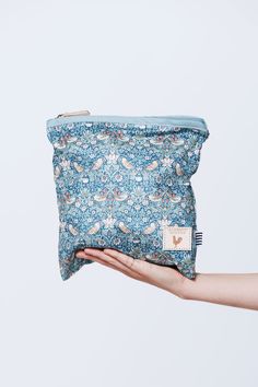 Model's hand holding a medium sized blue zippered bag with a busy star and bird pattern Travel Fabric Bag With Zipper Pouch, Inexpensive Rectangular Bag With Strawberry Print, Summer Strawberry Print Bag For Daily Use, Strawberry Drawstring Bag, Casual Strawberry Print Rectangular Bag, Chicken Logo, Ditty Bag, Liberty Bag, Waxed Canvas Backpack