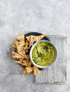 guacamole and tortilla chips on a black plate with a napkin