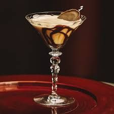 a dessert in a glass on top of a red plate with chocolate sauce and a spoon