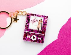 an mp3 player keychain with a photo on it and a star charm attached to it