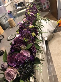 purple flowers and greenery are lined up on the counter