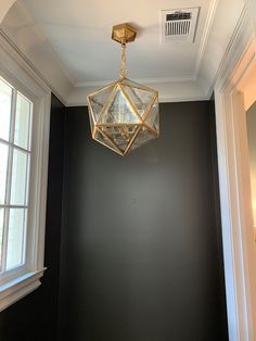 a light fixture hanging from the ceiling in a room with black walls and white trim