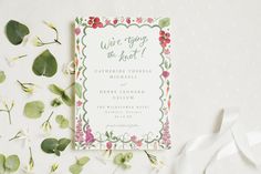 the wedding stationery is surrounded by flowers and greenery