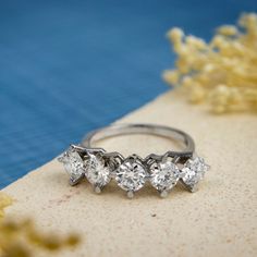 three diamond rings sitting on top of a table next to yellow flowers and seaweed