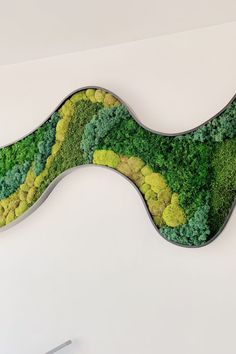 a green and yellow piece of art with trees on it's back side, in the shape of a wave