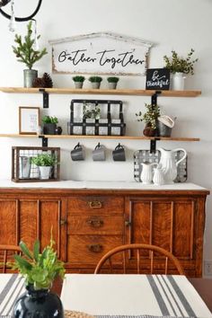 a dining room table with potted plants on top of it and shelves above the table