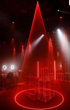 red light is shining on the floor in front of a stage with chairs and lights