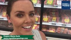 a woman standing in front of a display of hotdogs at a grocery store