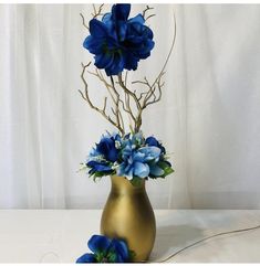 a gold vase filled with blue flowers on top of a table