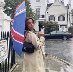 a woman standing on the sidewalk holding an umbrella