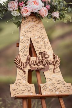 a wooden easel with flowers and writing on the top that says, the anniversary