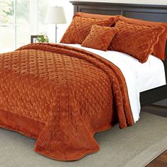 an orange bedspread and pillows in a bedroom