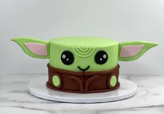 a green cake with a star wars yoda face on it's top and brown leather belt around the waist