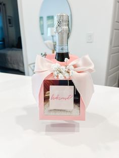 a bottle of champagne sitting on top of a table next to a card holder with flowers