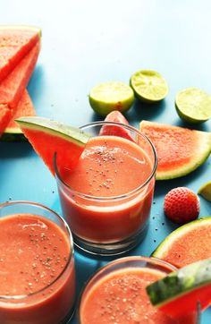 three glasses filled with watermelon and lime juice on top of a blue table