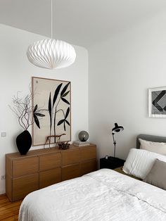 a bedroom with a bed, dresser and art work on the wall above it's headboard