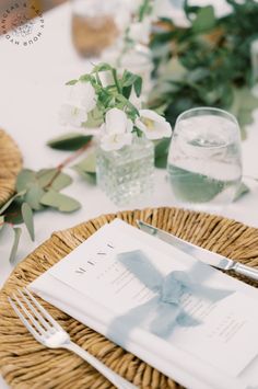 the table is set with white flowers and place settings for two people to sit at