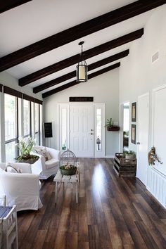 a living room filled with white furniture and wooden flooring next to a doorway that leads to a covered patio