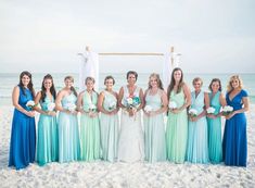 a group of women standing next to each other on top of a white sandy beach