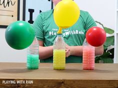 a man sitting at a table with balloons and plastic bottles in front of him on the table