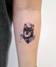 a small dog tattoo on the left inner forearm and arm, with blue flowers around it