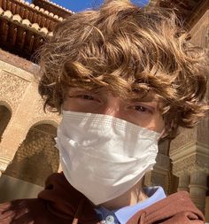 a young man wearing a face mask in front of a building with arches and pillars