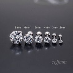 four pairs of diamond stud earrings on a black surface