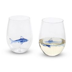 two wine glasses with shark designs on the bottom and one is filled with white wine