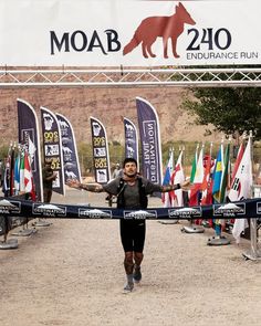 a man running across a cross country course with flags behind him and a dog on the other side of the finish line